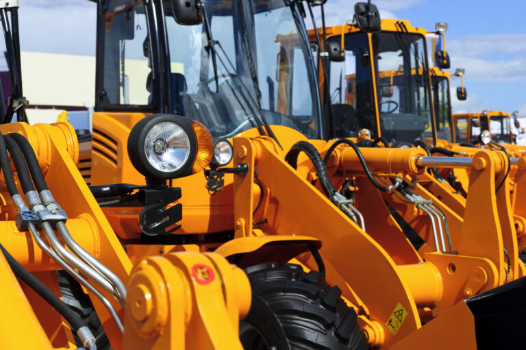 row of huge orange powerful construction machines, tractors, excavators,