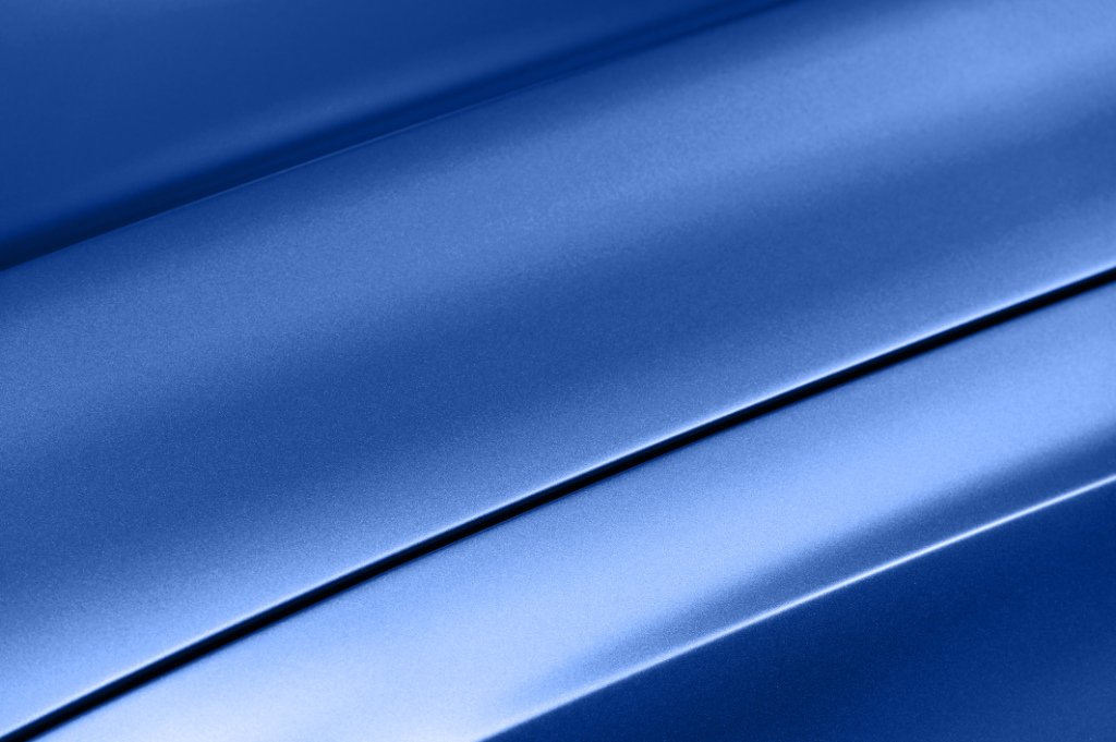 Surface of blue sport sedan car metal hood, part of vehicle bodywork, steel gradient line pattern, selective focus